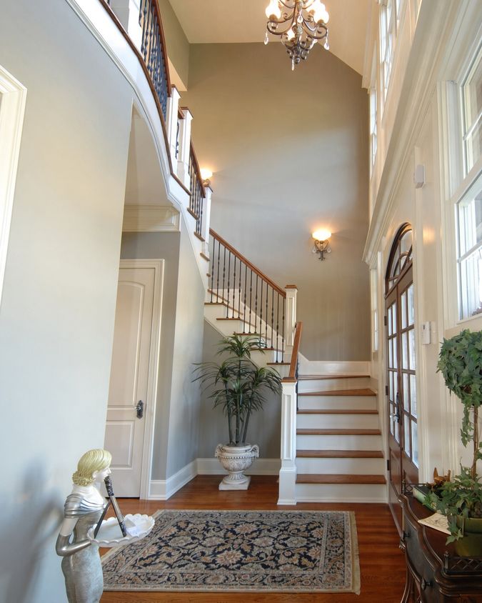 Bright hallway with soft grey-green walls, white woodwork and an oak staircase rising to a gallery landing.